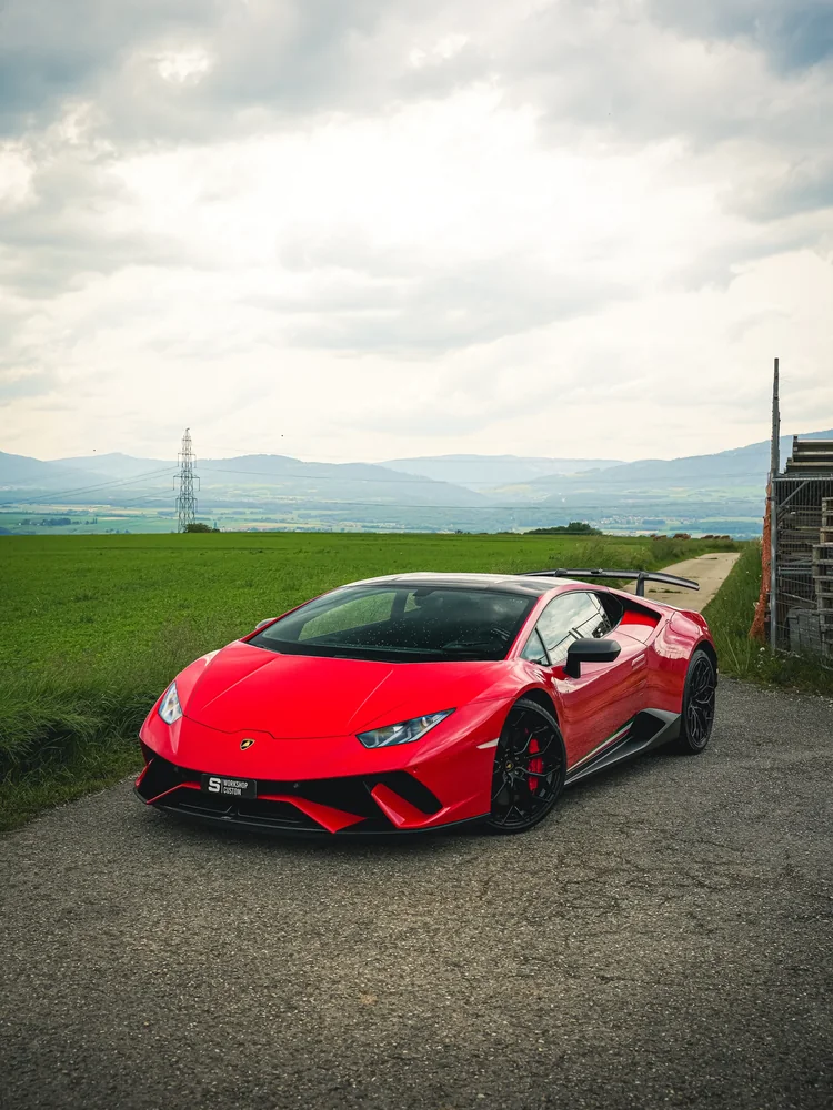 Lamborghini Huracán Performante rouge de trois quarts avant, champs et montagnes
